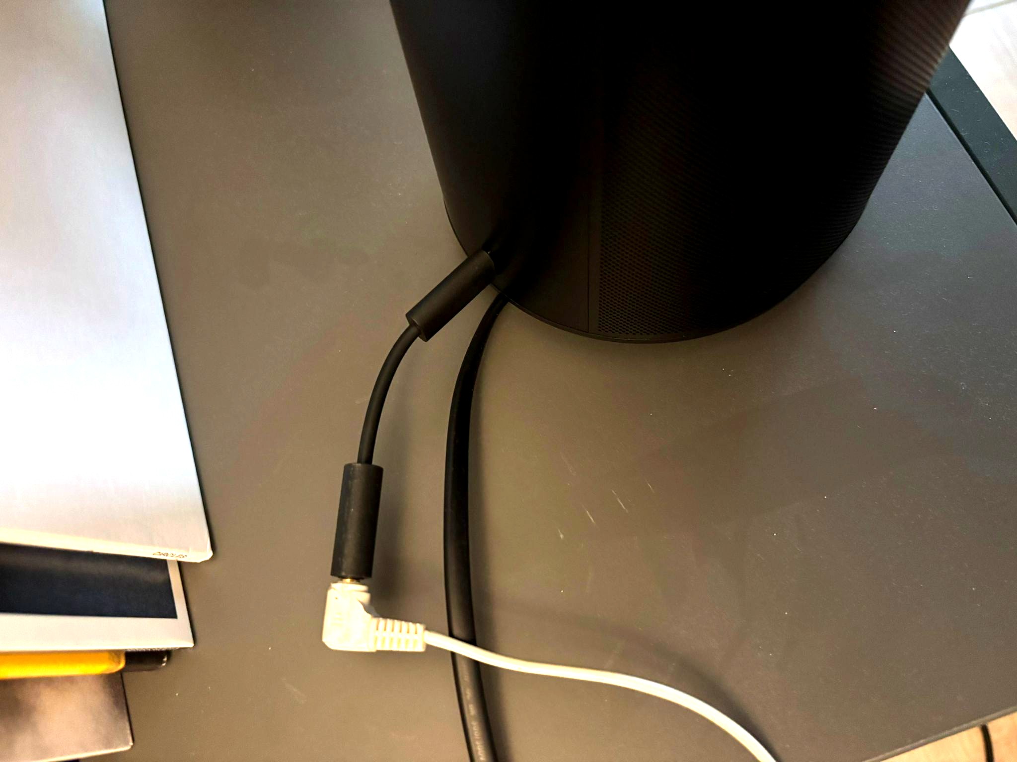 The Sonos Line-In Adapter cable connected to the back of a Sonos Era 100 speaker