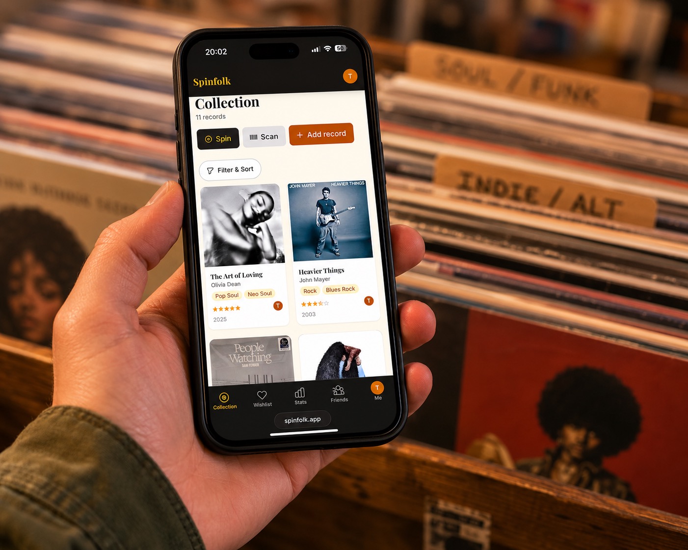 Checking the Spinfolk vinyl collection app on a phone above a crate of records