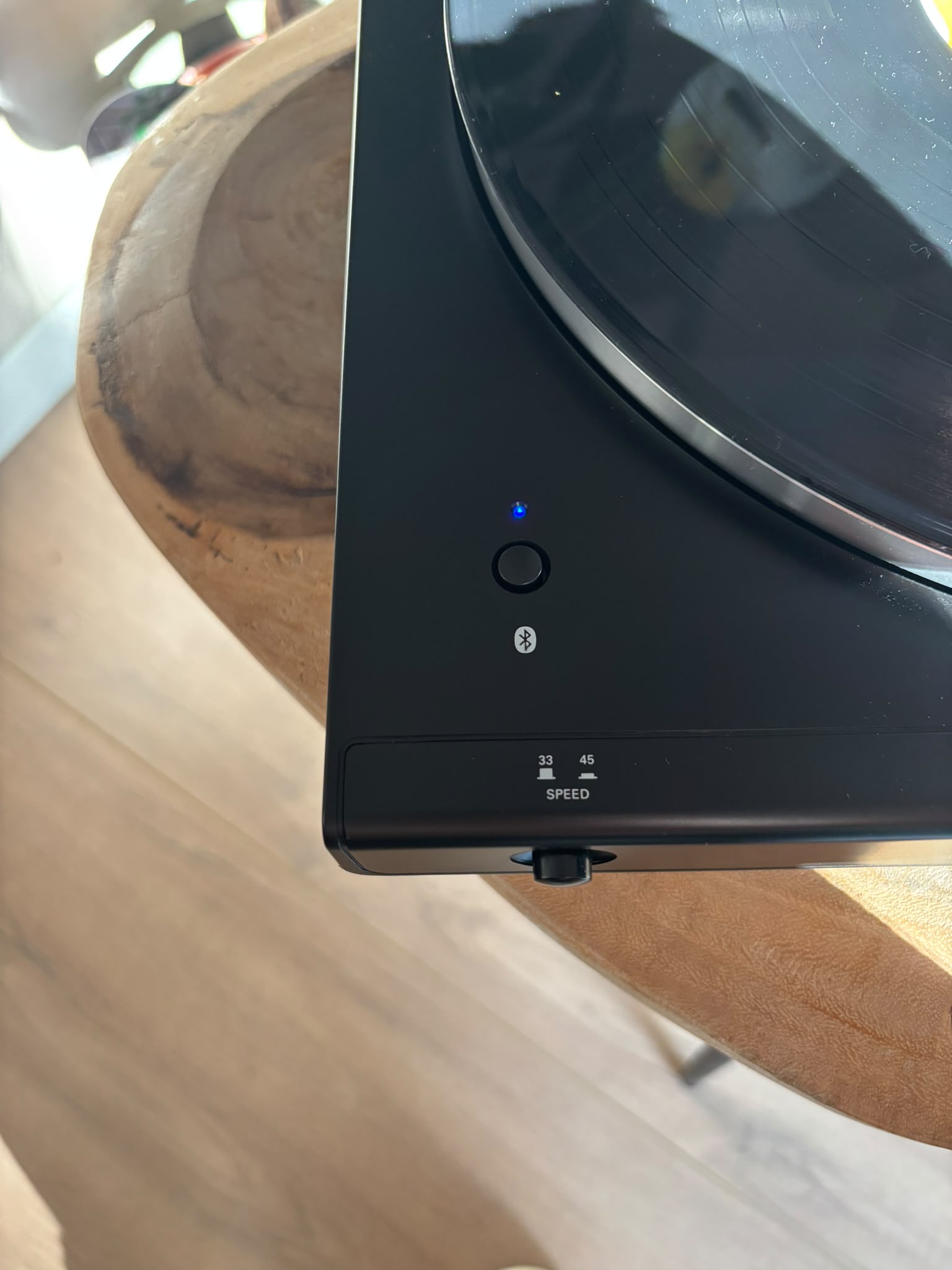Close-up of the turntable's Bluetooth button, light solid blue once paired