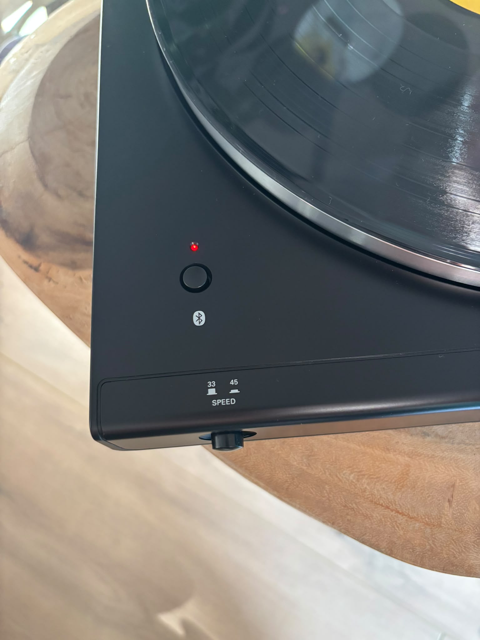 Close-up of the turntable's Bluetooth button, light flashing red while searching